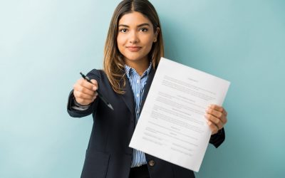 Confident young female professional with contract and pen against colored background